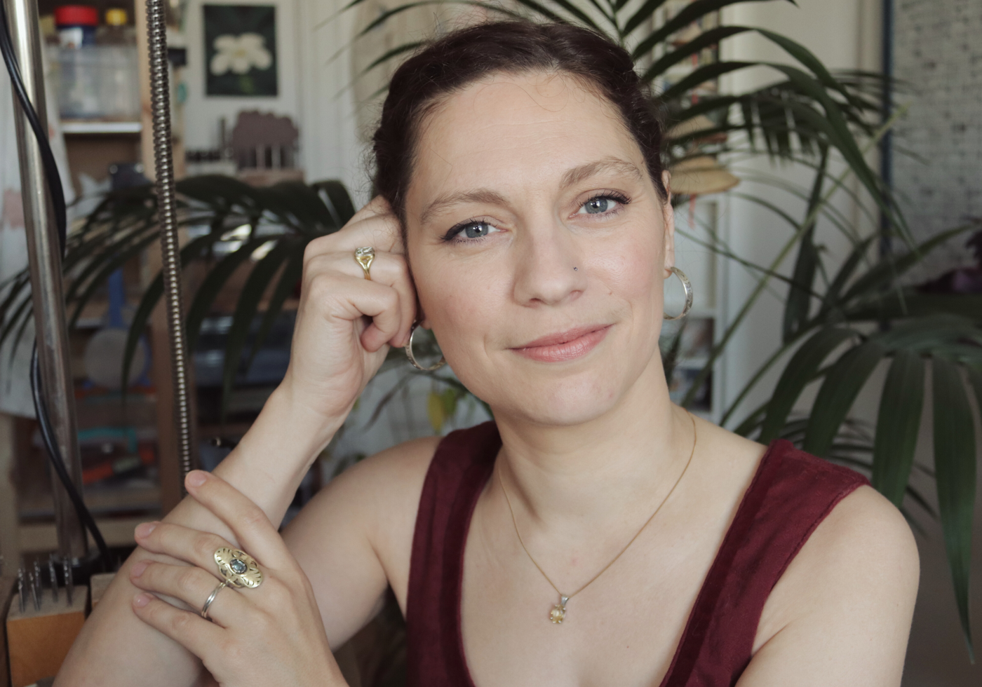 A portrait of Marion Chartier from Casez Jewellery in her workshop, wearing two gold rings, a silver ring and a citrin pendant.